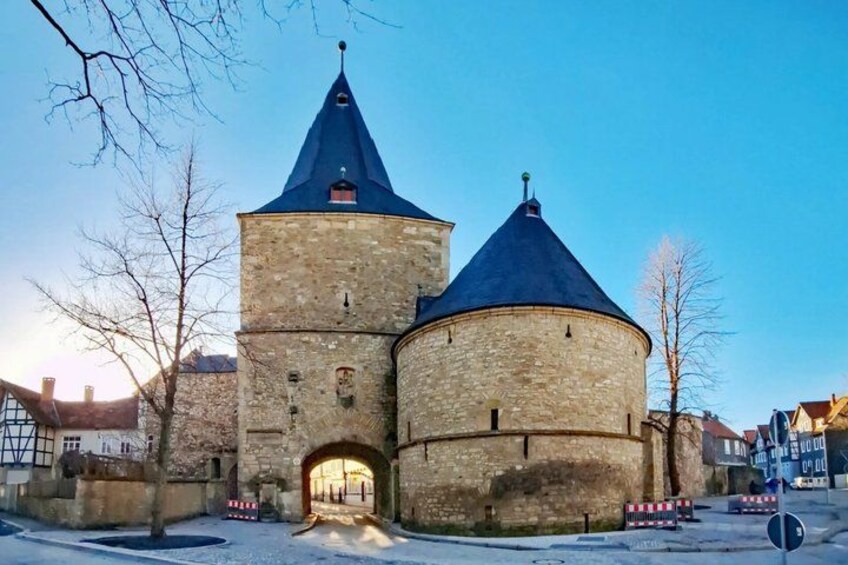A historic stone tower with a conical roof, surrounded by snow-covered ground and bare trees. 2