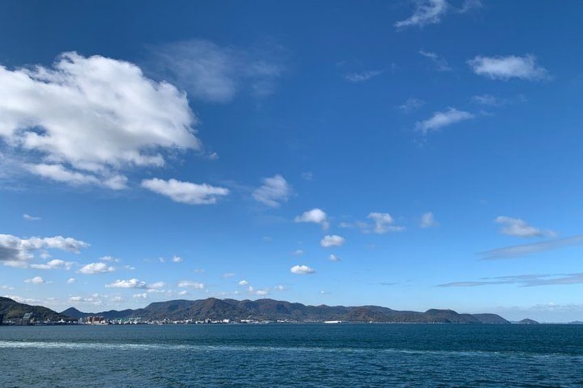 A coastal landscape with a clear sky, calm sea, and distant mountains. 1