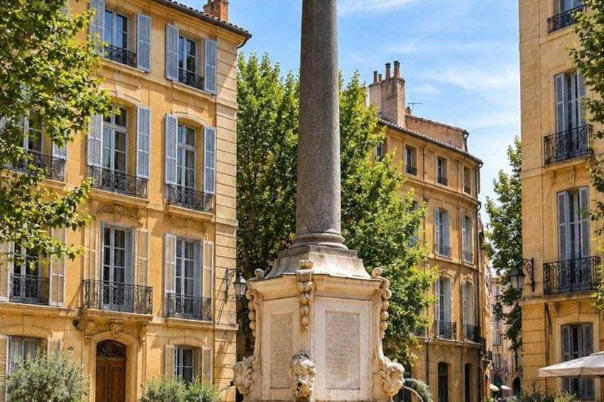A street with buildings, a column, and trees. 4