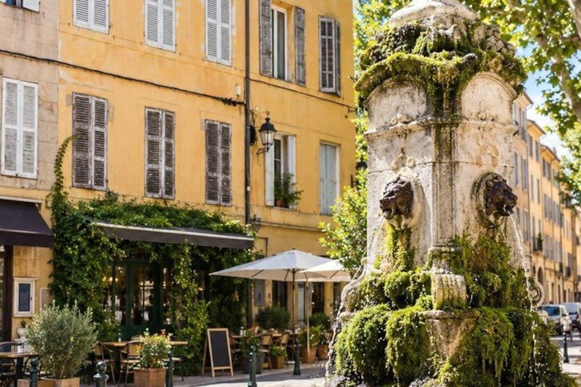 A European street with a fountain, yellow buildings, and outdoor seating. 5