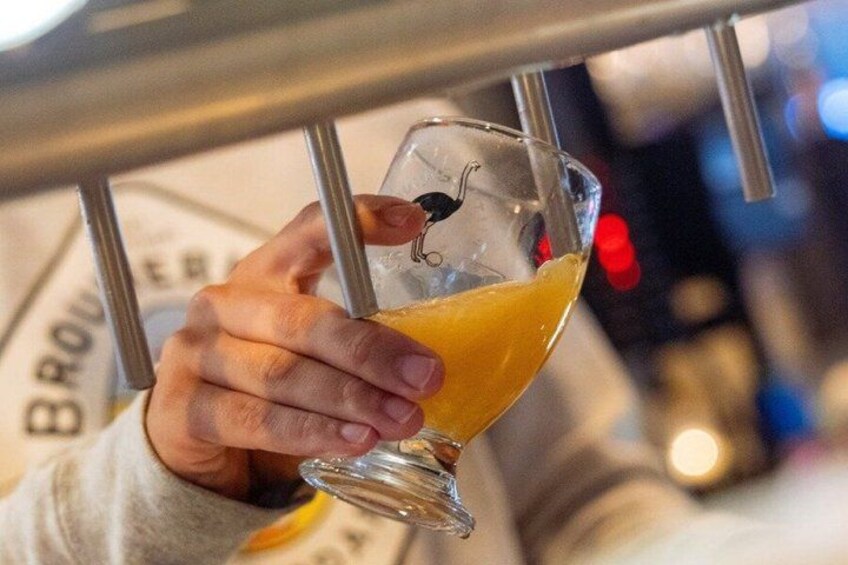 A person holding a glass with a yellow liquid, possibly a drink, in a bar setting. 3
