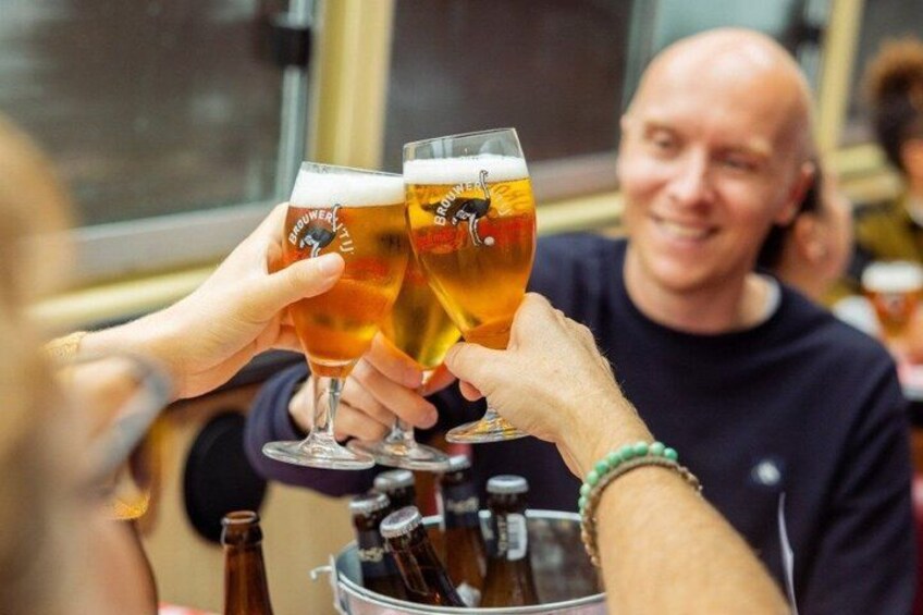 Two people toasting with beer glasses in a bar setting. 1