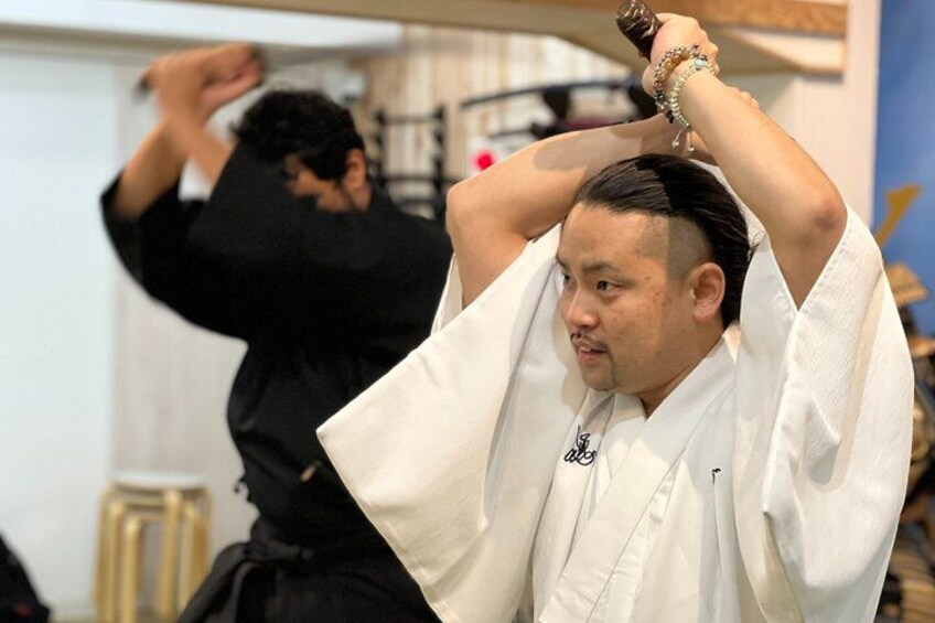 A person in a white martial arts uniform performing a technique with a weapon. 2