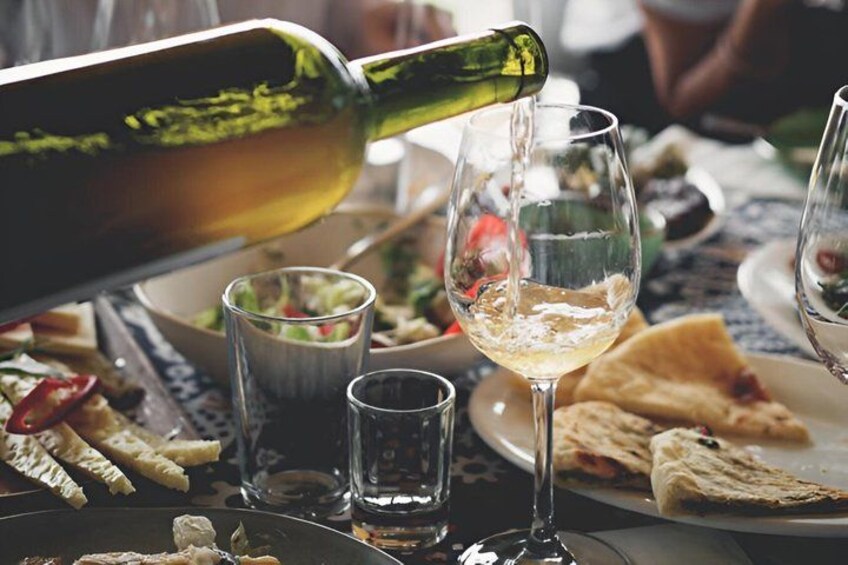 A bottle pouring wine into a glass, a salad bowl, and plates with food. 5