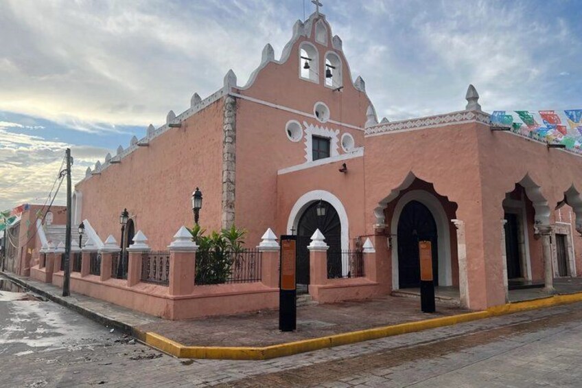 A pink colonial-style building with arched doorways and a bell tower. 2