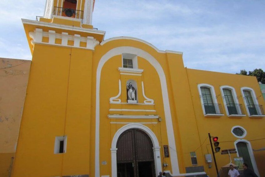 A yellow building with a bell tower and arched windows. 4