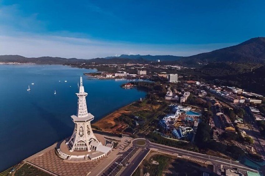 A coastal town with a prominent white tower, a large body of water, and surrounding hills. 5
