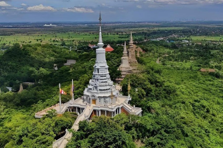 A large, white, multi-tiered pagoda surrounded by lush greenery and smaller structures. 1
