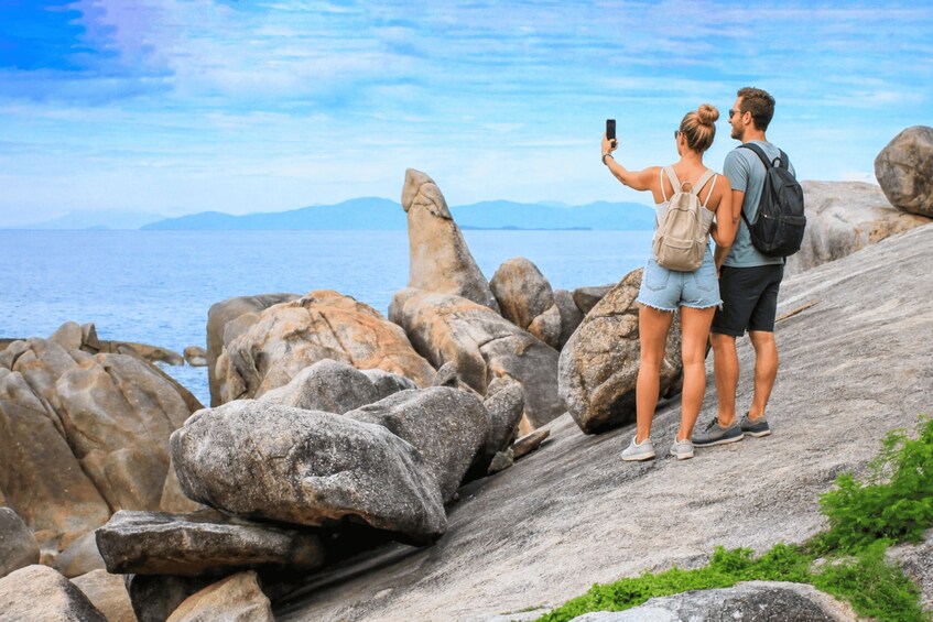 A couple taking a selfie on a rocky seaside with a clear sky. 4