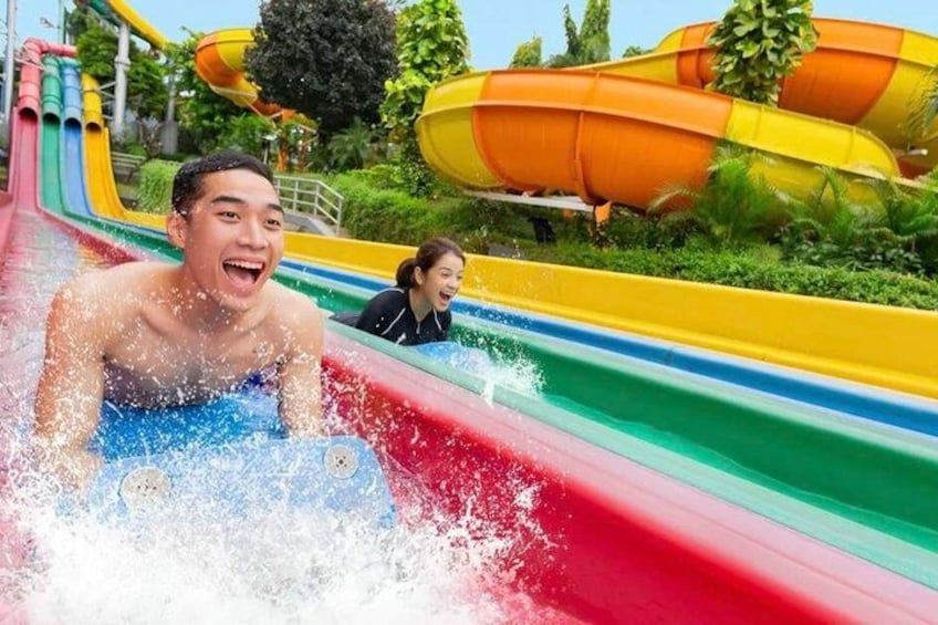 A water park with a red water slide and a yellow and orange water slide in the background. 1