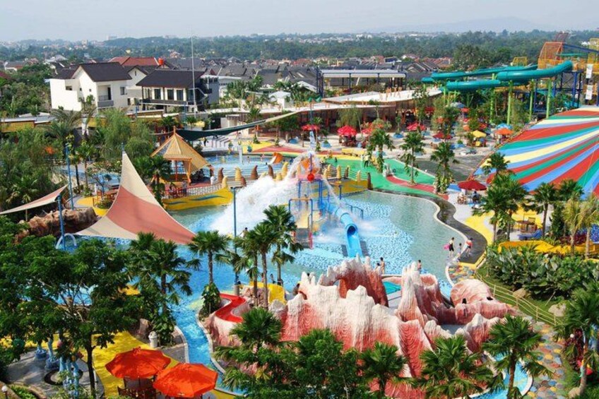 A water park with a large pool, slides, and artificial rock formations. 1