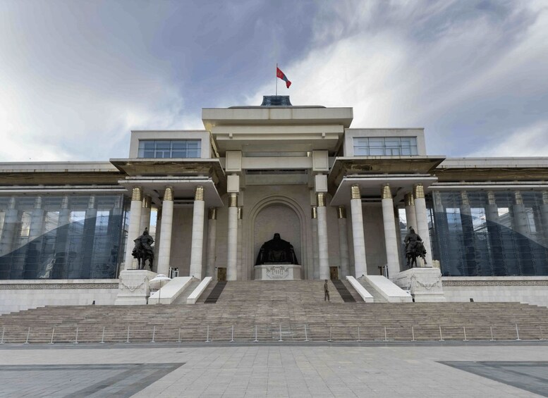 Un edificio imponente con una entrada amplia, columnas y una bandera en la parte superior. 3