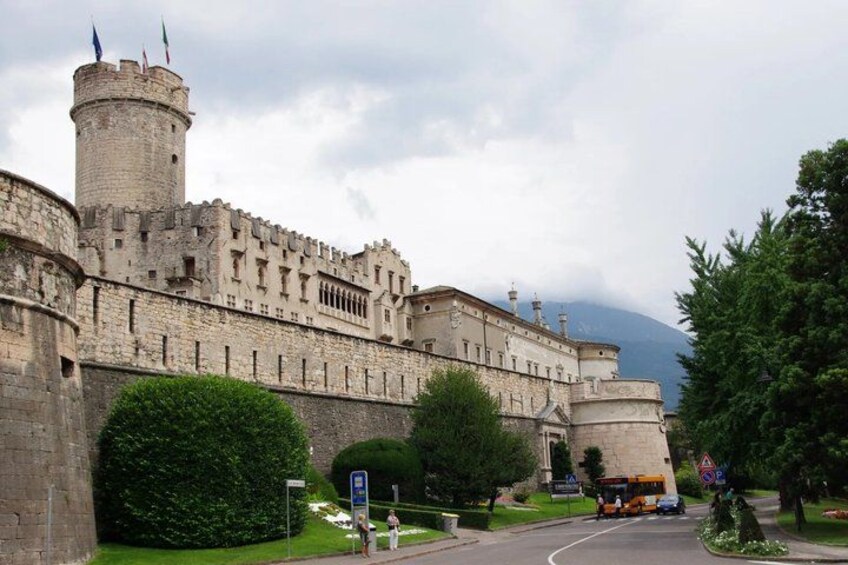 A historic castle with a round tower, surrounded by greenery and a road with vehicles. 2