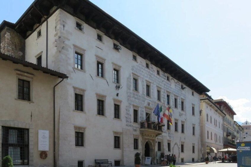 A historic building with multiple windows and flags, a signboard, and a clear sky. 5