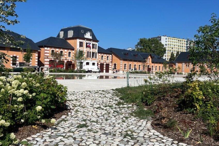 A stone pathway leading to a building with a red brick facade and a black roof. 3