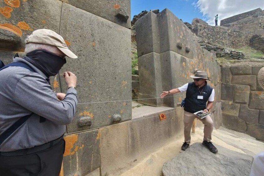 Two people examining ancient stone structures with inscriptions. 1