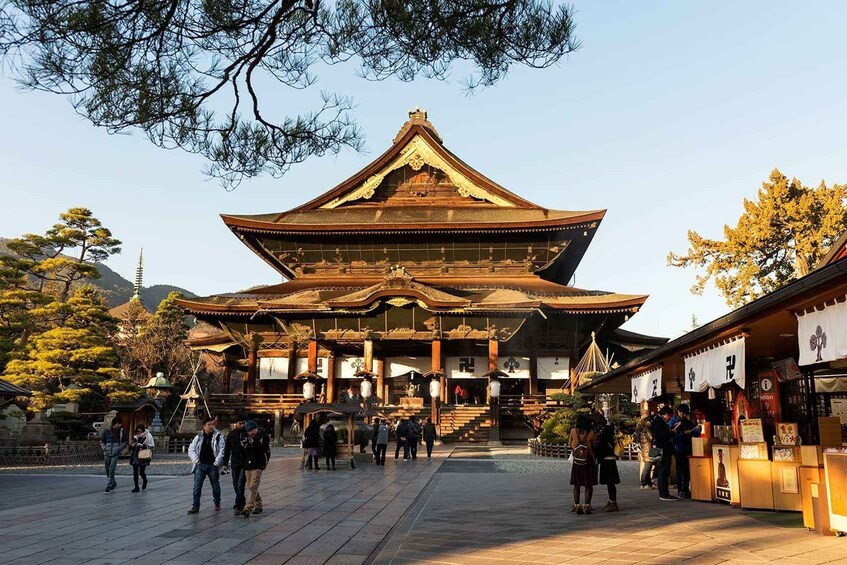 A traditional Japanese temple with a large, ornate roof, surrounded by people and trees. 5