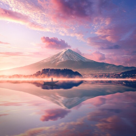 A mountain with a reflection in a calm body of water, surrounded by a misty landscape. 2