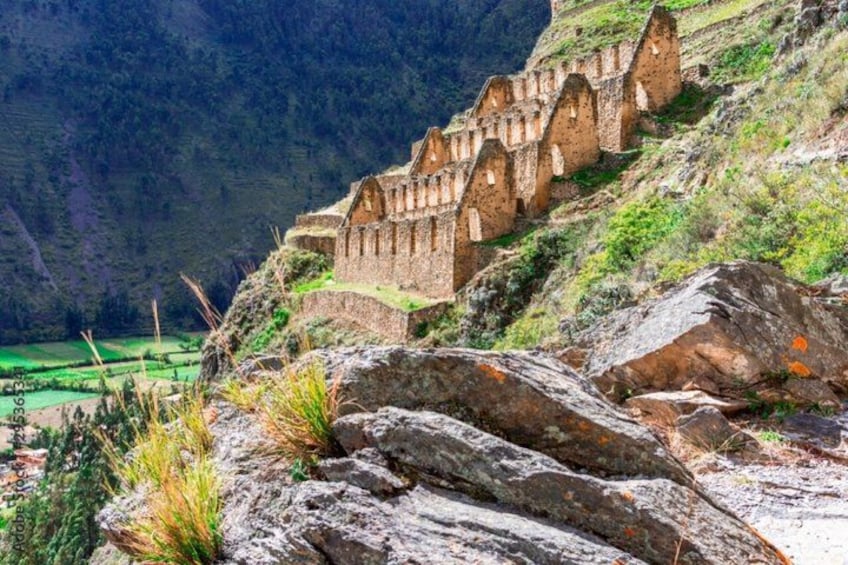 A historical stone structure with a series of arches, situated on a hillside with a valley in the background. 1