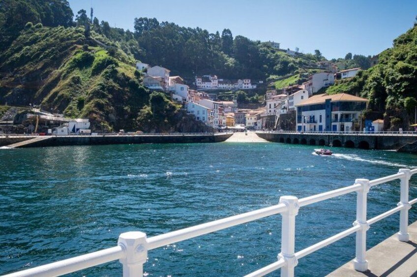 A coastal town with buildings on a hillside, a bridge, and a body of water. 4