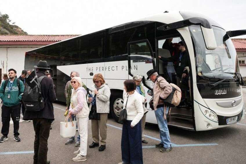 A group of people boarding a bus with 'The Perfect Plan' written on its side. 2
