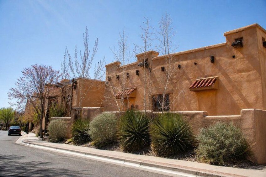 A building with stucco walls and red-tiled roofs, surrounded by cacti and desert vegetation. 2