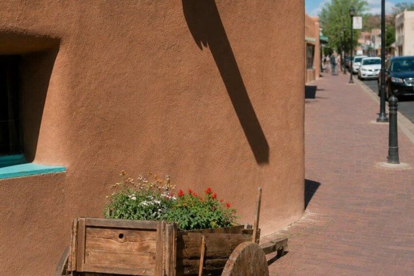 A building with a textured surface, a wooden planter with flowers, and a brick sidewalk. 5