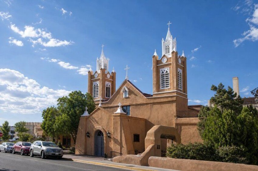 A church with two towers, a blue door, and parked cars. 4