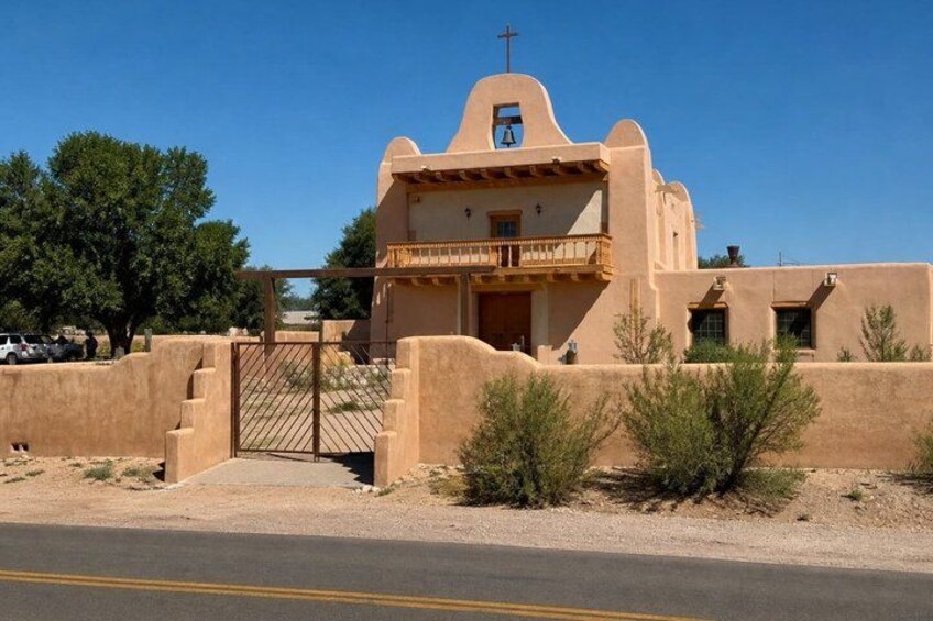 A single-story building with a flat roof, a cross on top, and a small balcony. 3