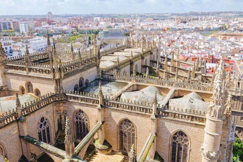 A Gothic cathedral with intricate architecture, a large open courtyard, and a cityscape in the background. 2