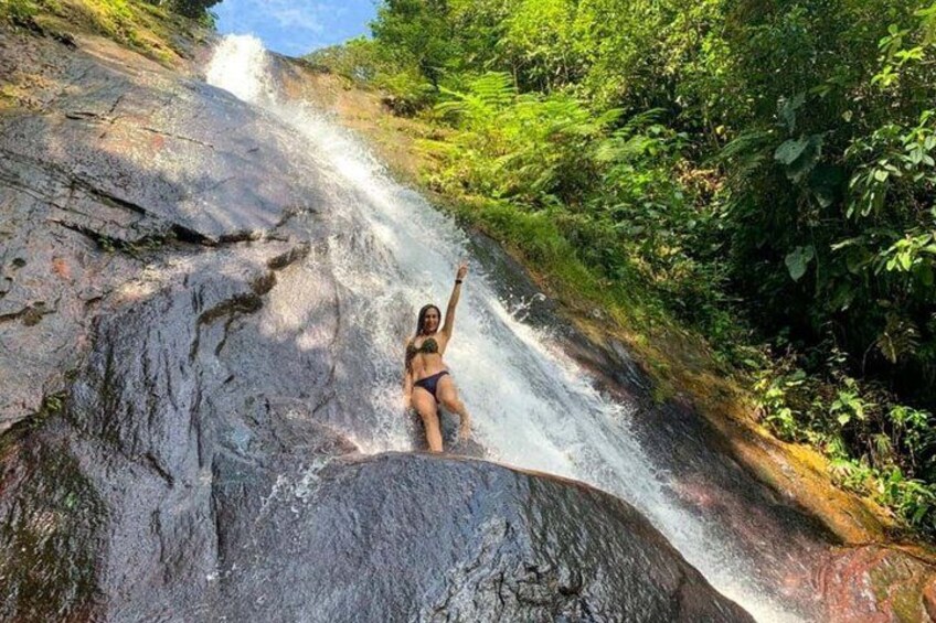 A person standing on a rock with a waterfall in the background. 5