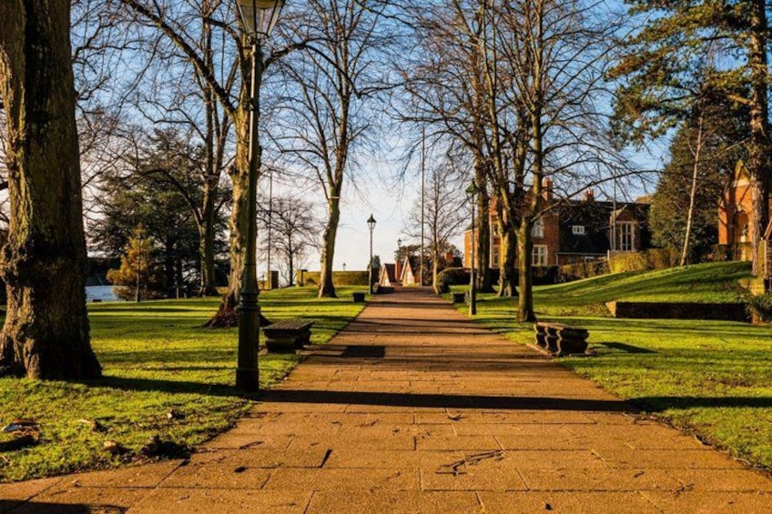 A paved pathway in a park with trees and grass on either side. 3
