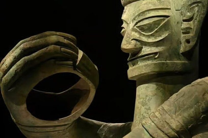 A bronze statue with a ring held by a hand. 1