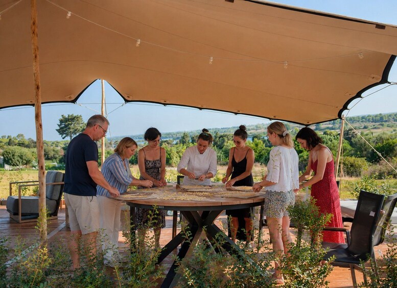 A group of people around a table under a canopy, engaged in an outdoor activity. 2