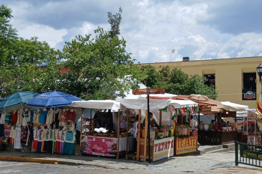 Outdoor market stalls with various goods and a building in the background. 2