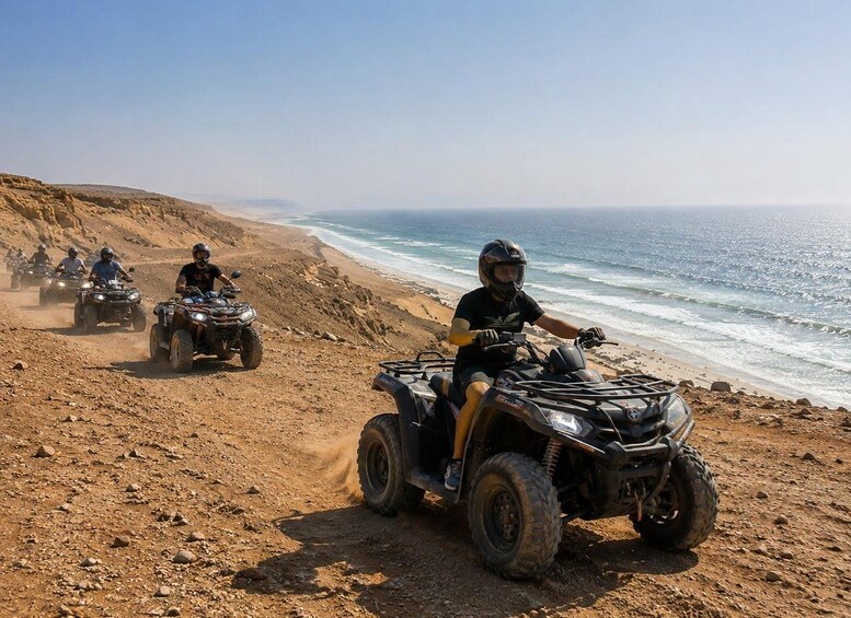 A group of people riding ATVs on a sandy beach with the ocean in the background. 2