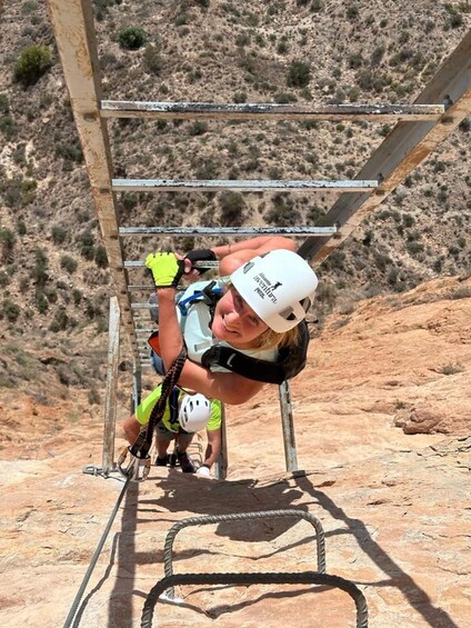 A person climbing a metal ladder in a rocky outdoor environment. 5