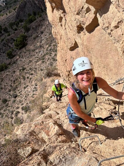 Two people climbing a rocky mountain with safety harnesses and helmets. 3
