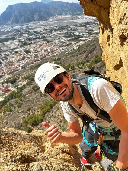 A person climbing a rocky mountain with a city in the background. 4