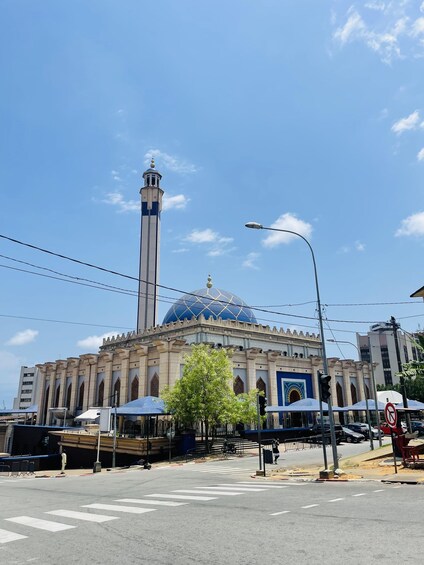 A mosque with a tall minaret and a large blue dome, surrounded by a street with traffic lights and a pedestrian crossing. 3