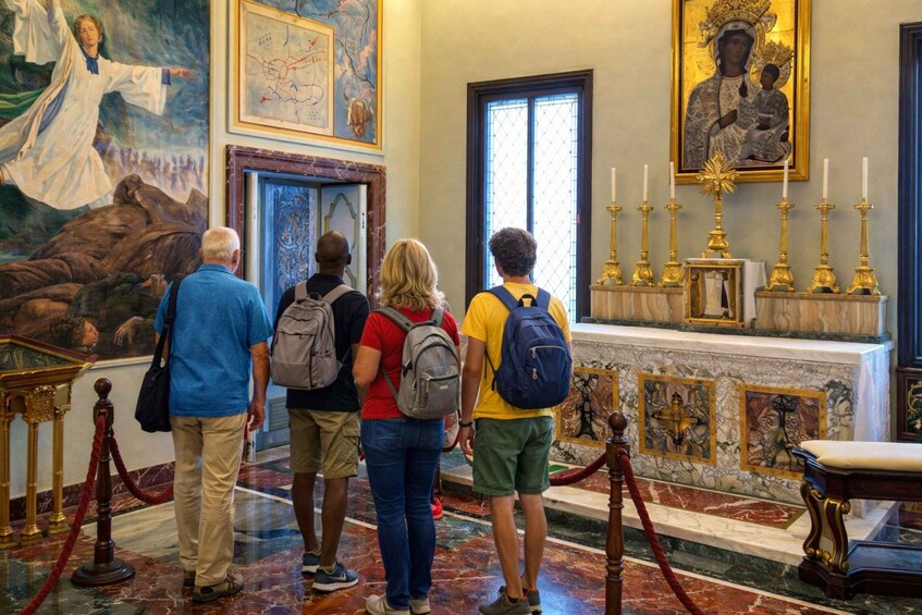 A group of people in a historical building with marble floors, a large painting of a woman, and religious icons. 3
