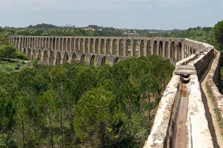 A long aqueduct with arches, surrounded by greenery and hills. 2