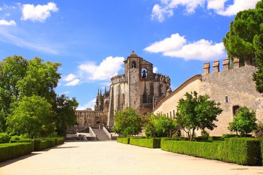 A historic stone building with a bell tower, surrounded by well-manicured hedges and trees. 5