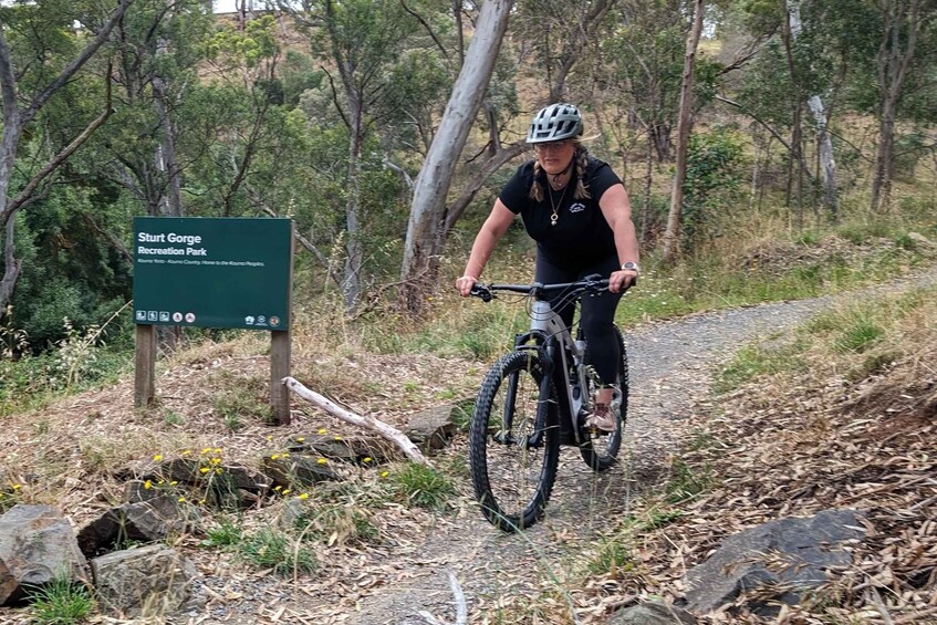 A person riding a mountain bike on a trail in a forested area with a sign for 'Start Gorge Recreation Park'. 2