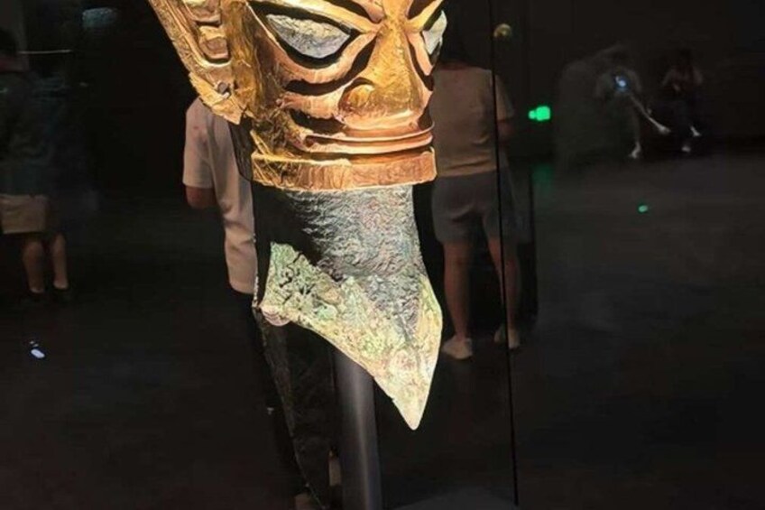A large, intricately carved wooden sculpture with a golden finish, displayed in a museum setting. 3