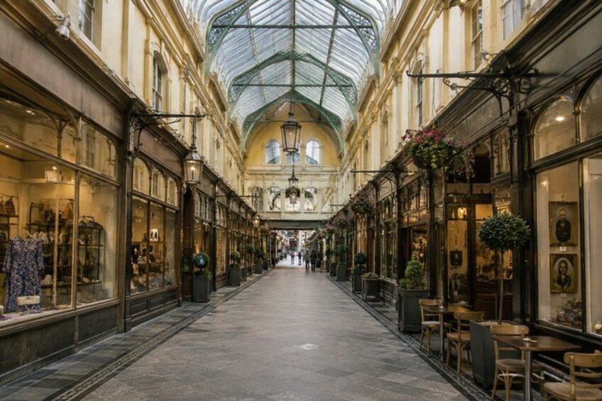 A covered shopping street with shops on either side and a glass ceiling. 5