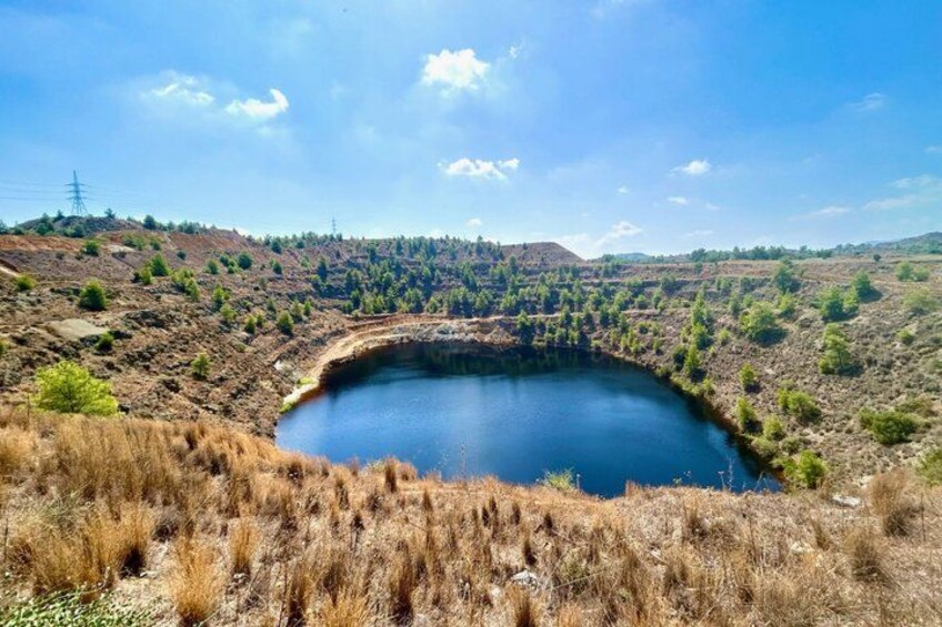 A large lake surrounded by dry grassland and sparse trees under a clear sky. 3