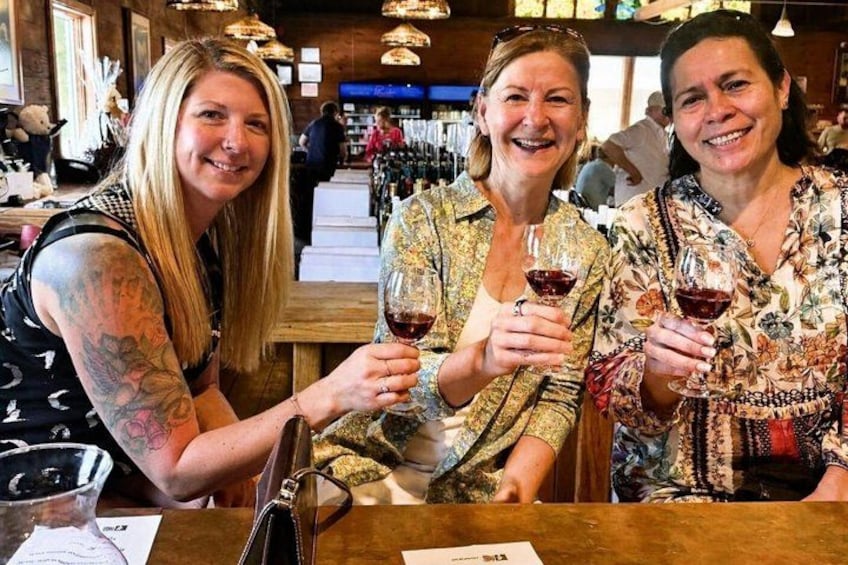 Three people sitting at a bar with wine glasses. 4