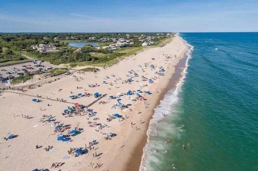 A beach with people sunbathing, umbrellas, and a clear sky. 5