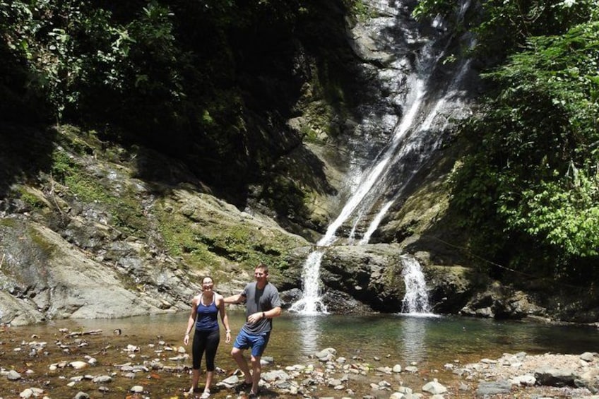 A waterfall, rocky terrain, and two people standing by a stream. 2